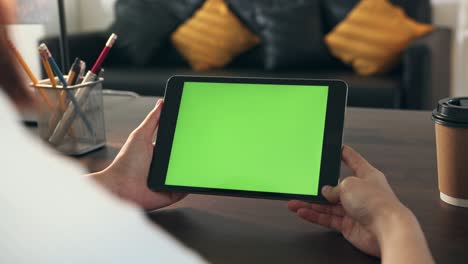mujer sosteniendo una tableta digital con pantalla verde y dispositivo táctil navegando por internet.