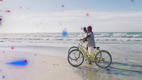 elderly couple walking bicycles along beach with colorful dots animation overlay