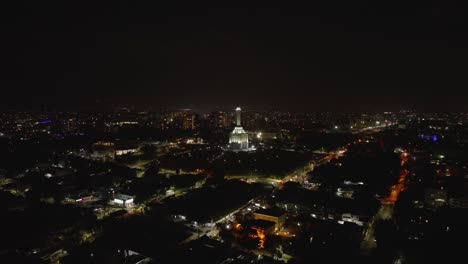 Aerial-View-of-Santiago-de-los-Caballeros,-Dominican-Republic-at-Night,-Monument-to-the-Heroes-of-Restauration-and-City-Lights