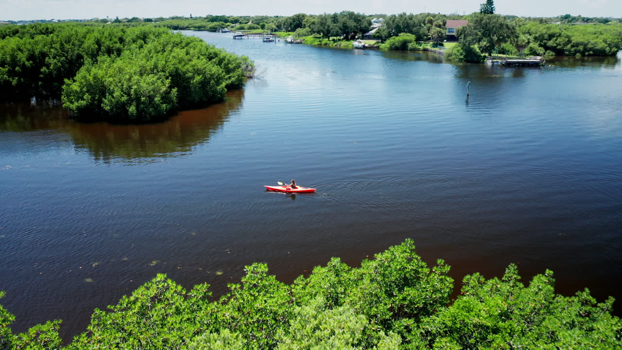 Aerial View of Female Kayaker Paddling Alone Across the River