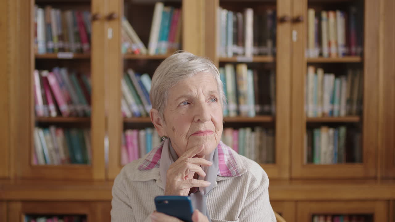 retrato de una mujer anciana pensativa en la biblioteca enviando mensajes de texto escribiendo usando la aplicación de mensajería de teléfonos inteligentes sonriendo feliz