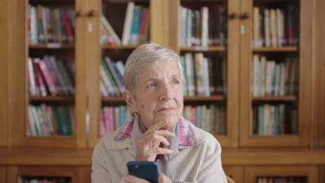 Porträt-Einer-Nachdenklichen-älteren-Frau-In-Der-Bibliothek,-Die-Mit-Der-Smartphone-Messaging-App-SMS-Schreibt-Und-Glücklich-Lächelt