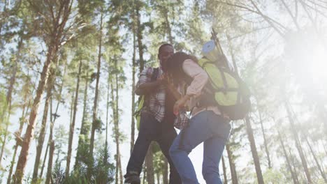 Smiling-diverse-couple-holding-hands-and-hiking-in-countryside