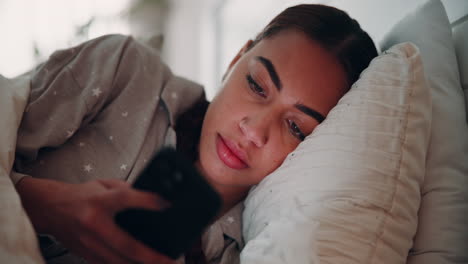 young woman relaxing in bed looking at phone
