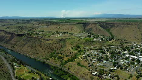 us, oregon, maupin, , 2025-05-08 - drone view of the city of maupin, hwy 197, and the deschutes river with a forest fire burning in the distance near mt hood near north central oregon