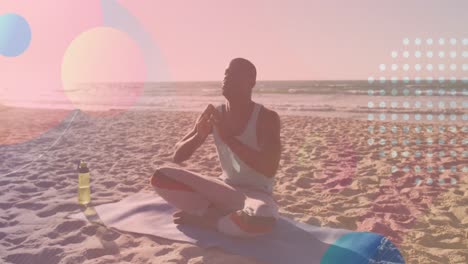 Animation of shapes over african american man meditating at beach