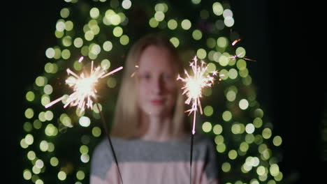 Happy-child-holding-sparklers,-standing-against-the-backdrop-of-a-Christmas-tree-at-home