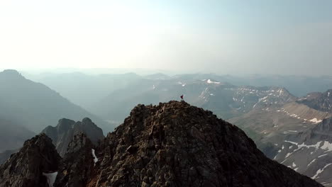 silueta de escalador parado en la cima de la cumbre con una vista majestuosa de la cordillera, vista aérea de drones