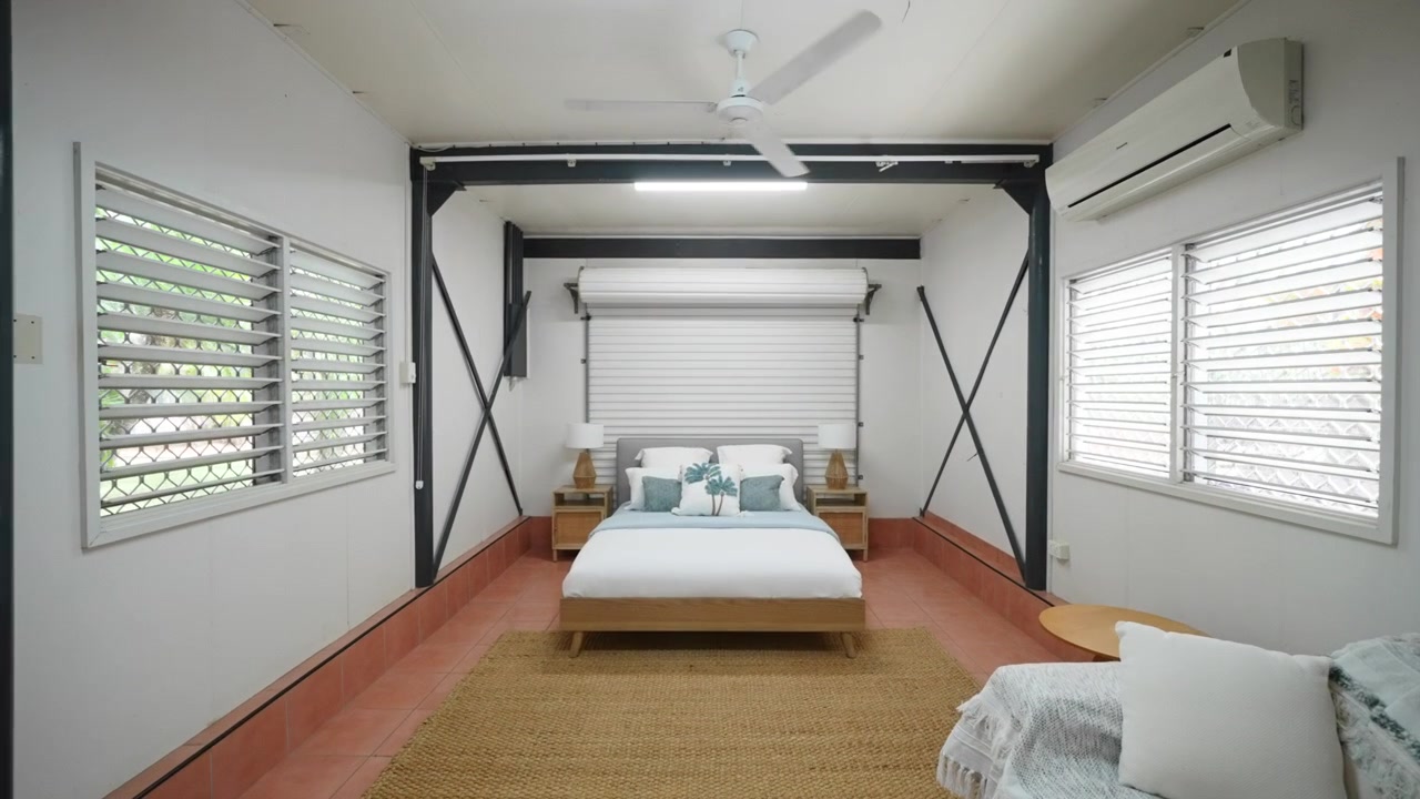 Garage convertito in camera da letto in una casa moderna con comodini tropicali. Interno di casa per annuncio immobiliare.