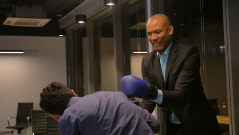 two competitive colleagues competitors fighting with boxing gloves in corporate office