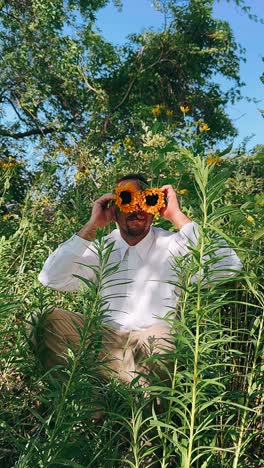 man with sunflower glasses in a field