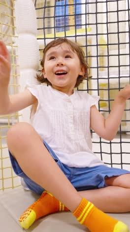 a close-up shot captures the pure joy and excitement on a little girl's face as she smiles and laughs while spinning on a ride at a modern indoor play center