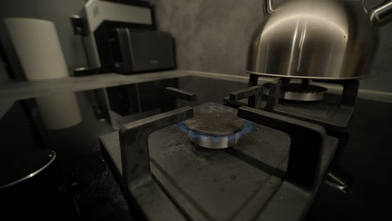 Bruciatore di fornello a gas che si accende con fiamma blu in cucina moderna.