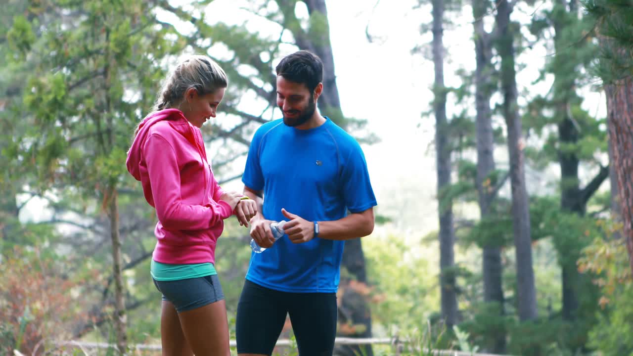 una pareja chequeando una hora en el bosque.