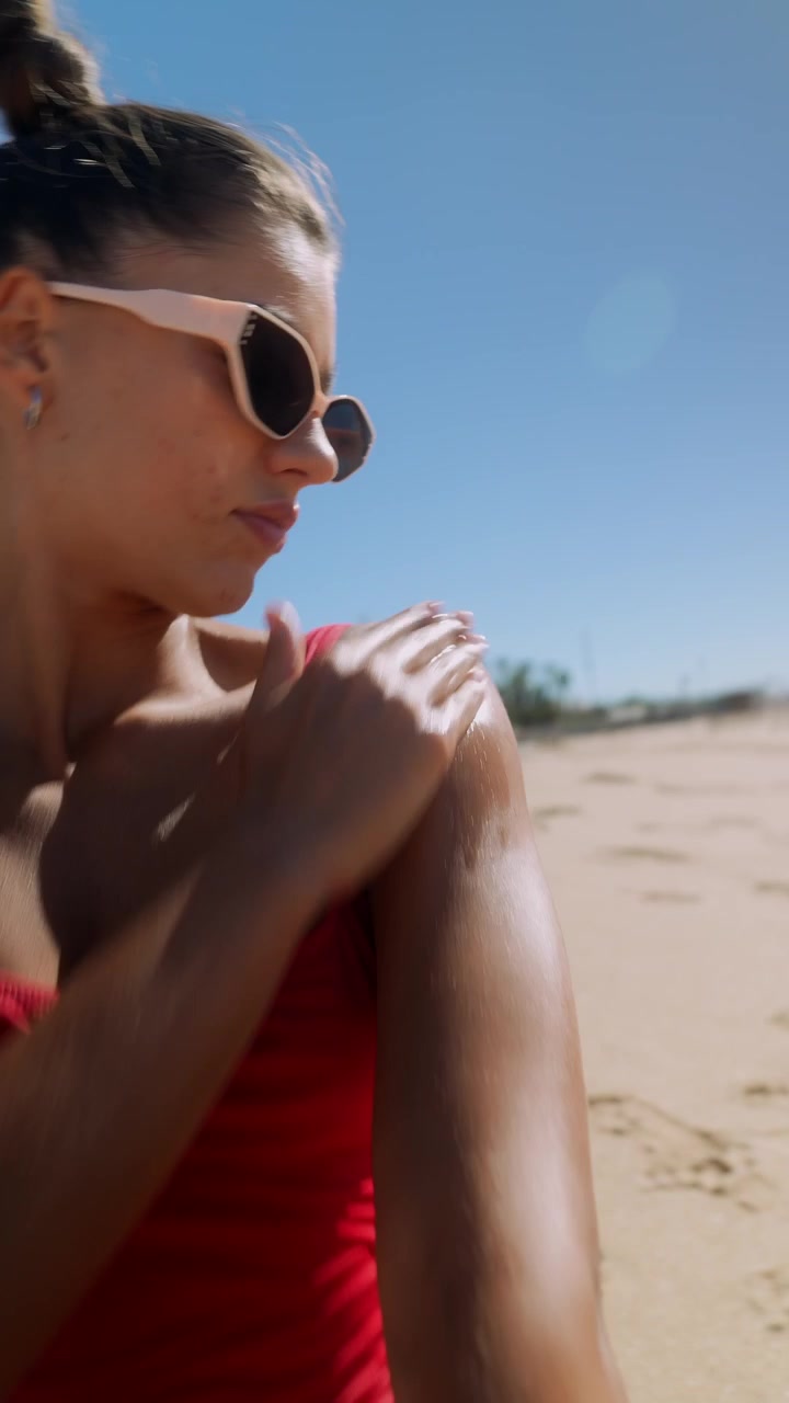 Young Woman Applying Sunscreen on Beach