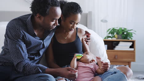 loving parents playing with baby daughter sitting on floor in bedroom