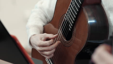 detalle de una guitarra clásica y manos femeninas tocando en ella