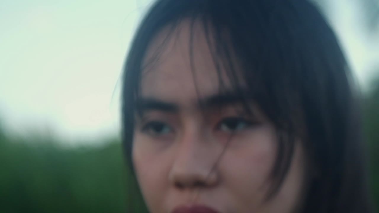 Slow-motion close-up shot of young woman's face and blank expression as she walks outdoors. -selective focus