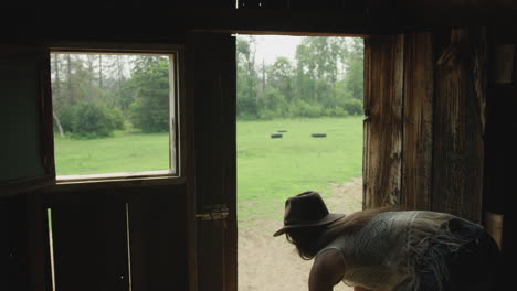 stylish cowgirl in horse barn tosses straw down to her horse-1