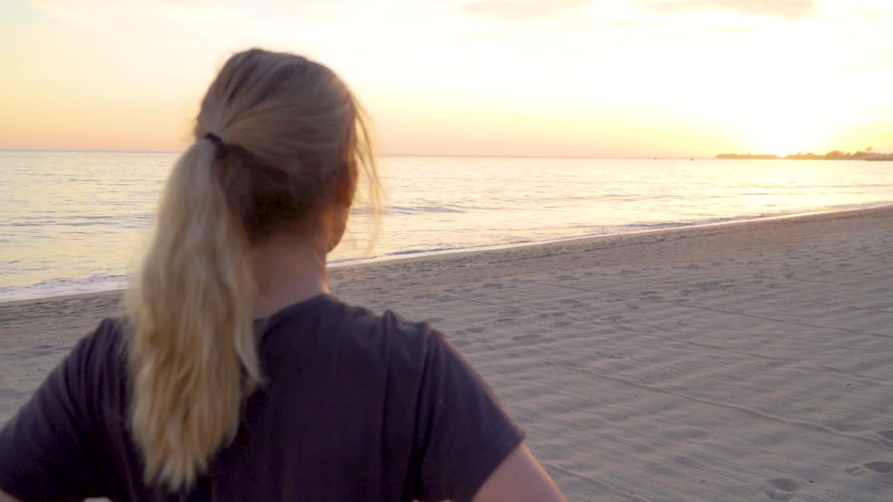 빈 해변에서 태양을 바라보는 여성