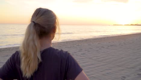 Female-looking-at-the-sun-setting-on-empty-beach