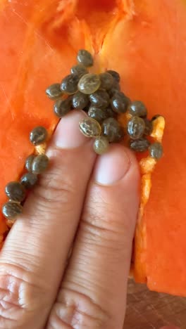hand removing seeds from a cut papaya