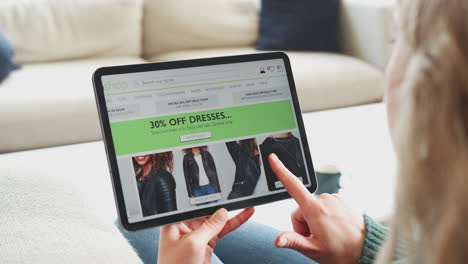 close up of woman shopping for clothes online using app on digital tablet