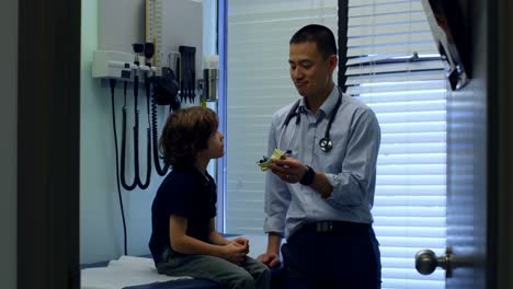 side view of young asian male doctor showing ear model to caucasian boy patient in clinic 4k