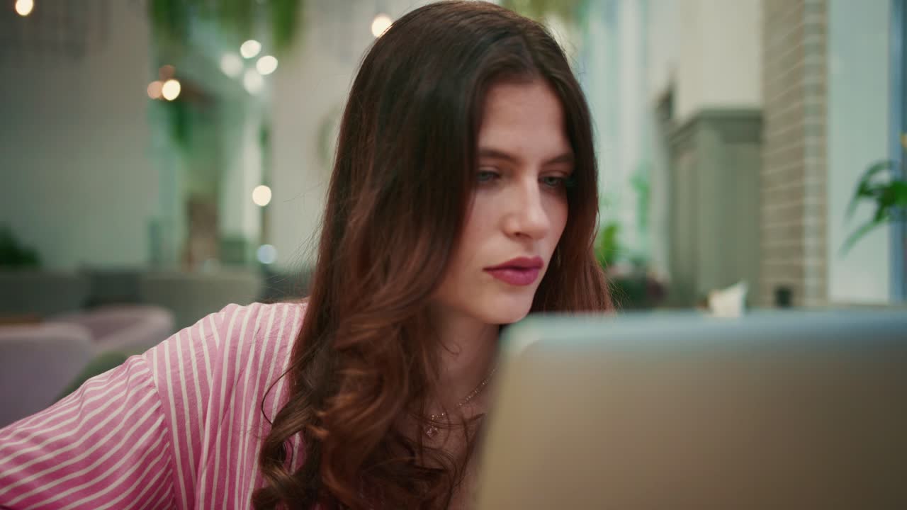 Young Woman Working on Laptop in a Modern Cafe