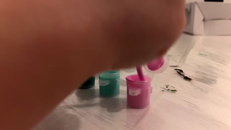 close-up. the boy soaks the brush in the paint container. painting at home. children's fun.