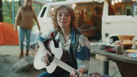 retrato de una mujer joven con una guitarra en el campamento