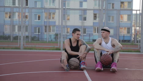 dos hombres sentados y hablando en una cancha de baloncesto