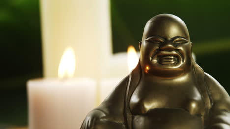 laughing buddha figurine with burning candles