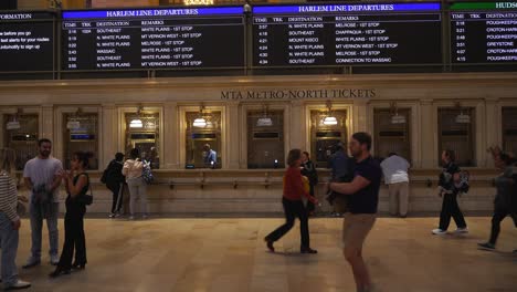 scene of passengers checking train schedules on the large departure board at grand central terminal
