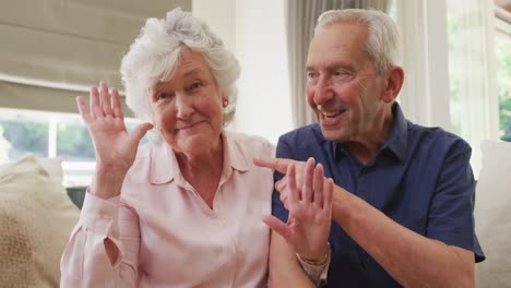 Portrait-of-senior-caucasian-couple-smiling-and-waving-to-camera
