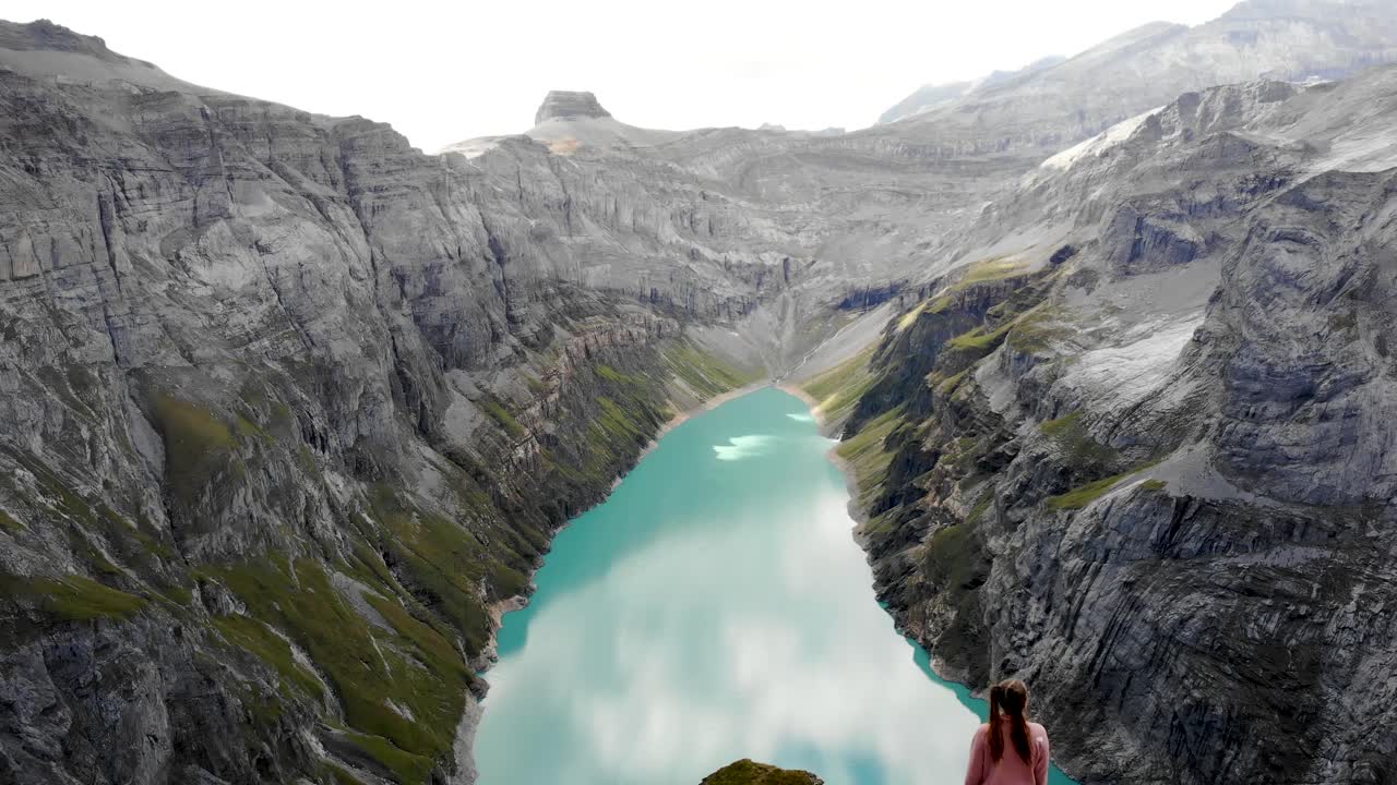 un paso elevado inverso sobre un excursionista que disfruta de la vista sobre el lago limernsee en glarus, suiza, cuyo agua color turquesa está rodeada por altos picos y acantilados de los alpes suizos
