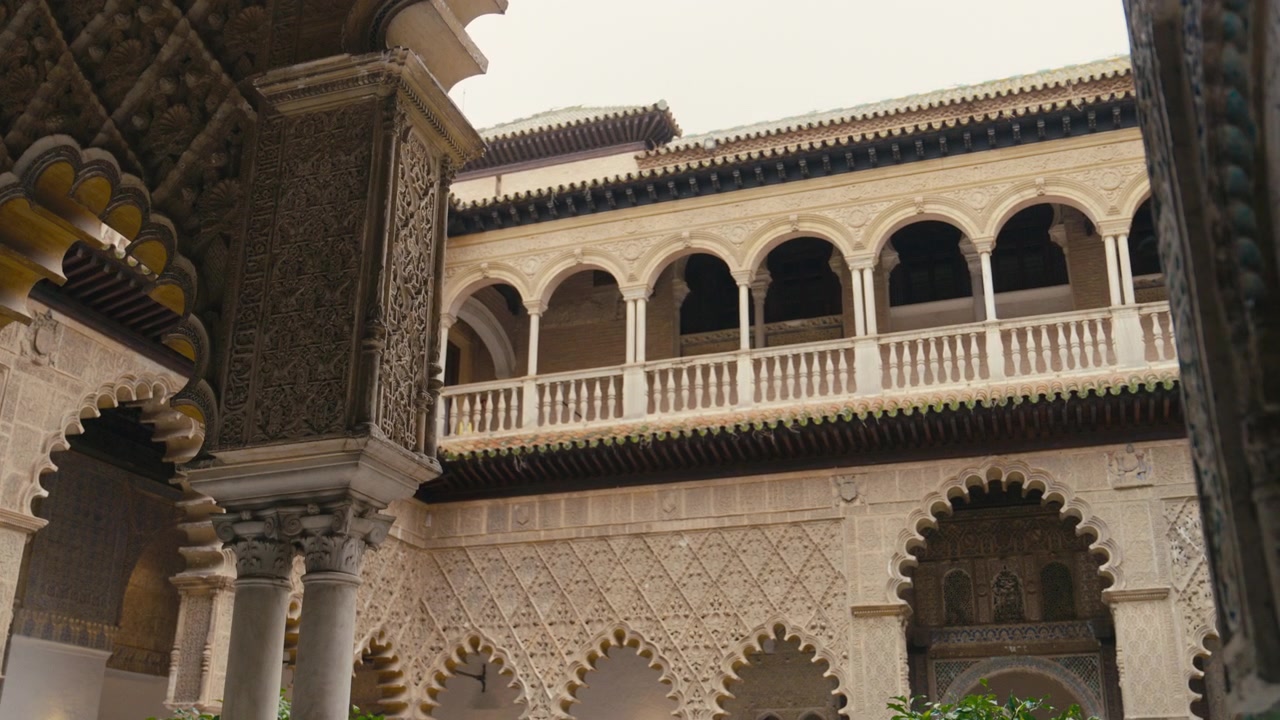 Vista di un cortile storico all'interno del Real Alcázar a Siviglia, Spagna, caratterizzato da un'intricata architettura moresca, archi intagliati e dettagli decorativi in pietra