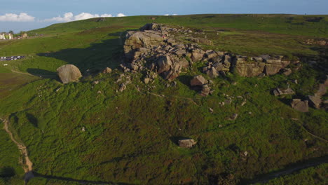 pullback establishing drone shot of cow and calf rocks rock formation on ilkley moor at golden hour west yorkshire uk