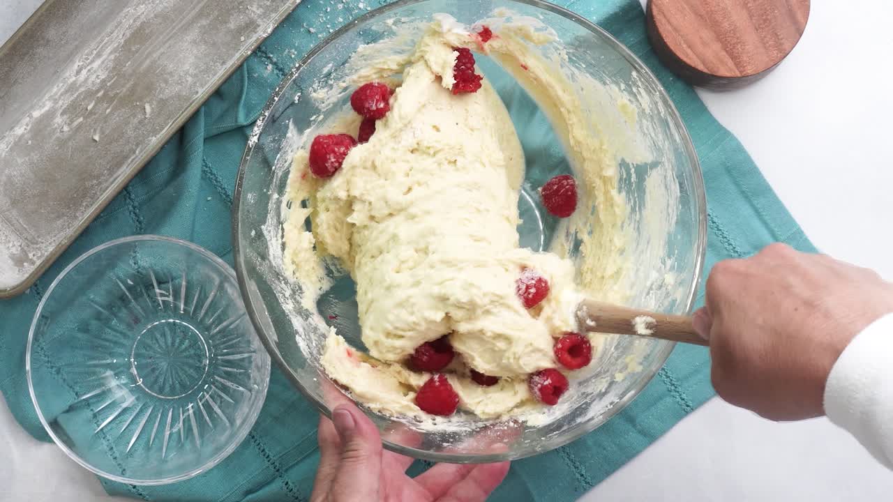 Making a dessert called Red Raspberry Tea Cake made with fresh berries and vanilla buttercream frosting. Great for Tea Parties. Adding into the batter, fresh red raspberries and mixing into the bowl