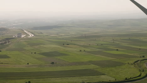 Rotating-wind-turbine-blades-above-agricultural-landscape-in-Georgia