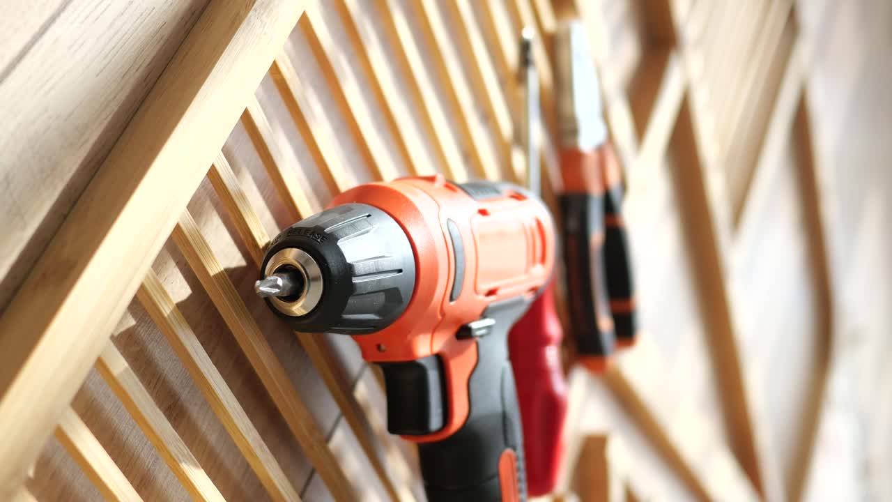Orange Electric Drill and Tools on Wooden Wall