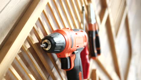 orange electric drill and tools on wooden wall