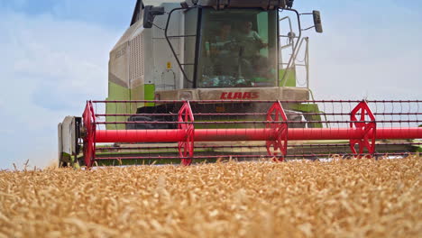 modern machinery gathering harvest on a sunny summer day. gradual close up to the mowing mechanism of a combine harvester.