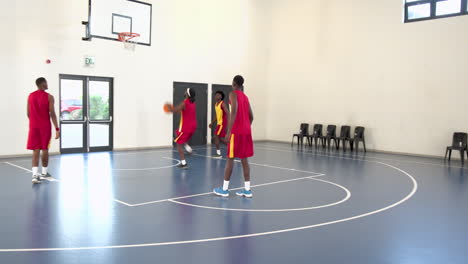 group of multiracial male basketball players playing basketball, passing and throwing in gym