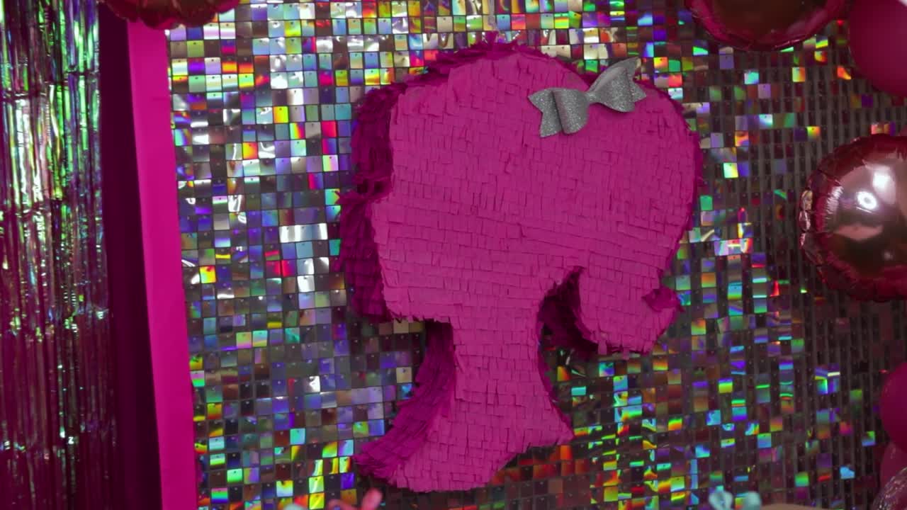 silueta de cabeza de muñeca rosa pinata contra telón de fondo holográfico con arco plateado