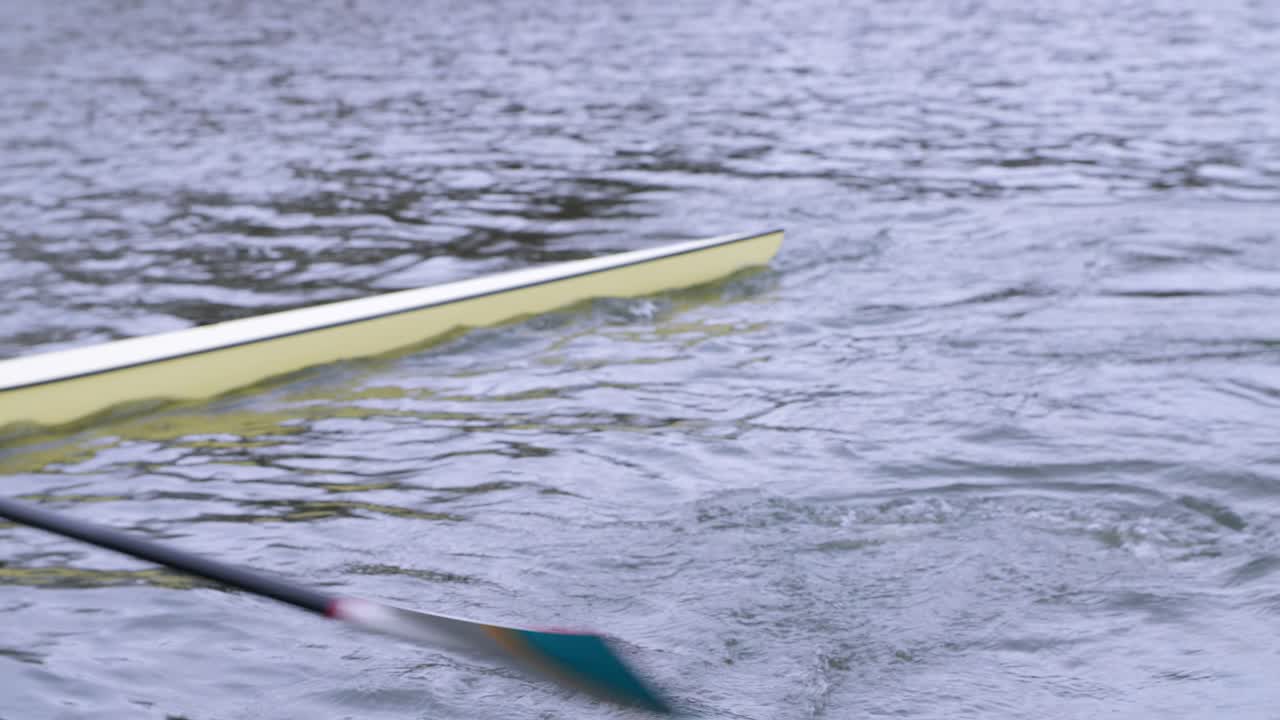 remero practicando la técnica de barrido en bote de remos de un solo cráneo con remo turquesa y blanco y bote de crema, a lo largo del canal de utrecht en los países bajos
