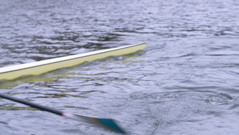 Rower-practising-sweep-technique-in-single-scull-rowing-boat-with-turquoise-and-white-oar-and-cream-boat,-along-the-Utrecht-canal-in-the-Netherlands