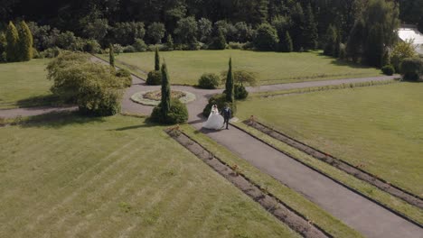 newlyweds, caucasian groom with bride walking, holding hands in park, wedding couple, aerial view