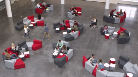 wide overhead shot of students in a busy university lobby, shot on r3d