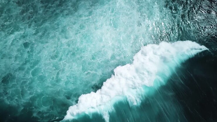 Dark Aerial shot of a huge powerful wave crashing on the choppy ocean waters
